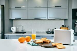 Portion of toasts on a wooden board with orange juice. Breakfast is served on a table with light blue napkin. photo