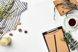 Blank opened notebook with cup of coffee on white table. Top view. Writing concept photo