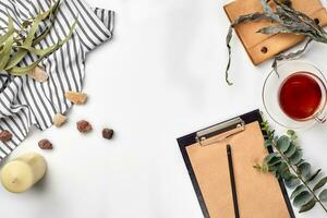 Blank opened notebook with cup of tea on white table. Top view. Writing concept photo