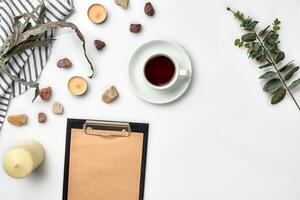 Blank opened notebook with cup of coffee on white table. Top view. Writing concept photo