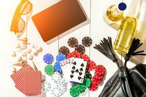 Card deck surrounded by poker chips and scattered seashells on white wooden background with copy space photo