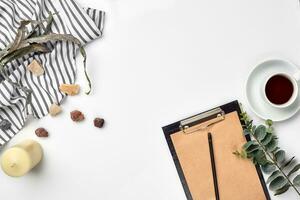 Blank opened notebook with cup of coffee on white table. Top view. Writing concept photo