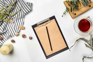 Blank opened notebook with cup of tea on white table. Top view. Writing concept photo