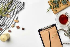 Blank opened notebook with cup of tea on white table. Top view. Writing concept photo