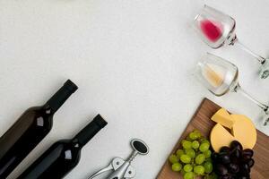 Two glasses of white and red wine, cheese and grapes. Top view photo