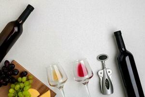 Glasses and bottles of red and white wine on white background from top view photo