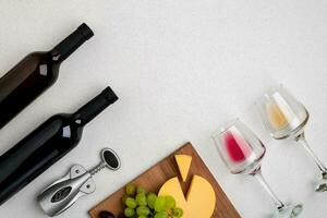 Two glasses of white and red wine, cheese and grapes. Top view photo