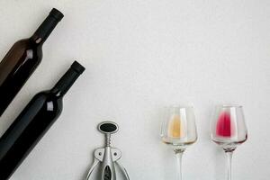 Glasses and bottles of red and white wine on white background from top view photo