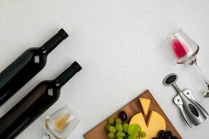 Two glasses of white and red wine, cheese and grapes. Top view photo