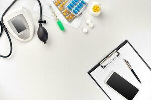 Top view of doctor's desk table, blank paper on clipboard with pen, electronic manometer to measure the blood pressure. photo