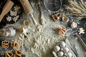 Cooking dough for cookies, butter, eggs, cooking equipment, flour on a black table. Top view with copy space, mockup for menu, recipe or culinary classes. Baking background. photo