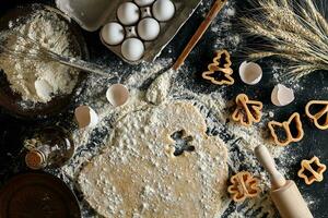 Dough for ginger biscuits rolled up on a table and cut using molds photo