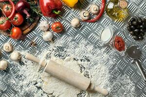 Ingredients and dough for making pizzas with an overhead view on freshly mixed mounds of pastry, a jar of olive oil and pot of tomato sauce, overhead view photo