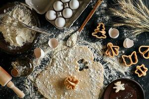 masa para jengibre galletas arrollado arriba en un mesa y cortar utilizando moldes foto