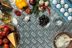 Food ingredients and spices for cooking pizza. Mushrooms, tomatoes, cheese, onion, oil, pepper, salt, egg, grater on metal background. Copy space. Top view photo