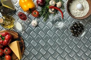 Food ingredients and spices for cooking pizza. Mushrooms, tomatoes, cheese, onion, oil, pepper, salt, egg, grater on metal background. Copy space. Top view photo