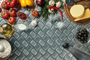 Food ingredients and spices for cooking pizza. Mushrooms, tomatoes, cheese, onion, oil, pepper, salt, egg, grater on metal background. Copy space. Top view photo