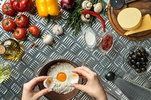 Set of ingredients for pizza and baker's hand smash eggs into bowl on metal table photo