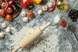 Ingredients and dough for making pizzas with an overhead view on freshly mixed mounds of pastry, a jar of olive oil and pot of tomato sauce, overhead view photo