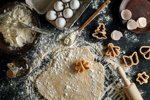 Dough for ginger biscuits rolled up on a table and cut using molds photo