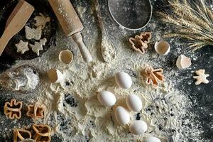 Cooking dough for cookies, butter, eggs, cooking equipment, flour on a black table. Top view with copy space, mockup for menu, recipe or culinary classes. Baking background. photo