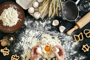 Woman smashes an egg using knife while kneading a pastry. Studio shot. Top view photo