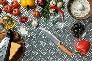 Food ingredients and spices for cooking pizza. Mushrooms, tomatoes, cheese, onion, oil, pepper, salt, egg, grater on metal background. Copy space. Top view photo