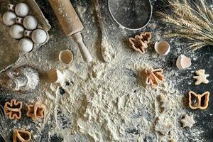 Cooking dough for cookies, butter, eggs, cooking equipment, flour on a black table. Top view with copy space, mockup for menu, recipe or culinary classes. Baking background. photo