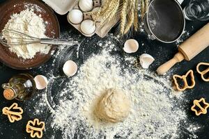 Cooking dough for cookies, butter, eggs, cooking equipment, flour on a black table. Top view with copy space, mockup for menu, recipe or culinary classes. Baking background. photo