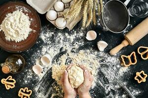 Woman's hands knead dough on table with flour, eggs and ingredients. Top view. photo