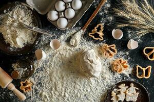 Cooking dough for cookies, butter, eggs, cooking equipment, flour on a black table. Top view with copy space, mockup for menu, recipe or culinary classes. Baking background. photo