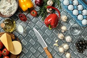 Food ingredients and spices for cooking pizza. Mushrooms, tomatoes, cheese, onion, oil, pepper, salt, egg, grater on metal background. Copy space. Top view photo