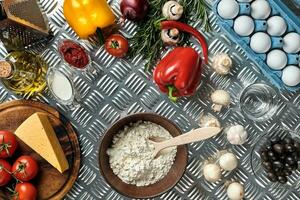 Food ingredients and spices for cooking pizza. Mushrooms, tomatoes, cheese, onion, oil, pepper, salt, egg, grater on metal background. Copy space. Top view photo