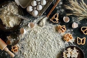 Cooking dough for cookies, butter, eggs, cooking equipment, flour on a black table. Top view with copy space, mockup for menu, recipe or culinary classes. Baking background. photo