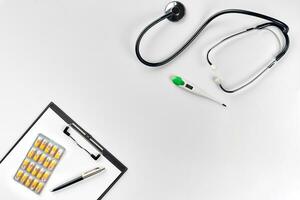 Stethoscope in the office of doctors.Top view of doctor's desk table, blank paper on clipboard with pen. Copy space. Designer's blank photo