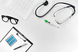 Stethoscope in the office of doctors.Top view of doctor's desk table, blank paper on clipboard with pen. Copy space. Designer's blank photo