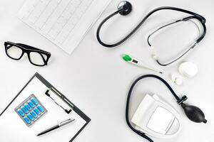 Stethoscope in the office of doctors.Top view of doctor's desk table, blank paper on clipboard with pen. Copy space. Designer's blank photo