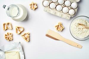 Objects and ingredients for baking, plastic molds for cookies on a white background. Flour, eggs, milk, butter, cream. Top view, space for text photo