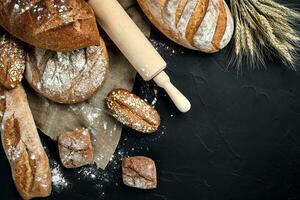 Bakery - gold rustic crusty loaves of bread and buns on black chalkboard background. photo