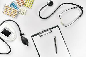 Stethoscope in the office of doctors.Top view of doctor's desk table, blank paper on clipboard with pen. Copy space. Designer's blank photo