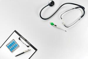 Stethoscope in the office of doctors.Top view of doctor's desk table, blank paper on clipboard with pen. Copy space. Designer's blank photo