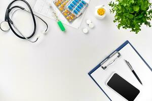 Stethoscope in the office of doctors.Top view of doctor's desk table, blank paper on clipboard with pen. Copy space. Designer's blank photo