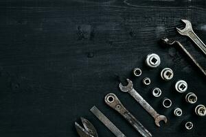 Copy space of working tools on a black wooden surface. Nippers, wrench keys, pliers, screwdriver. Top view. photo