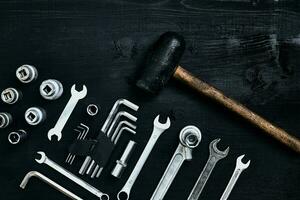 Renovating a car. A set of repair tools- hex keys, a hammer and a screwdriver on a black wooden background. Close up. Top view. photo