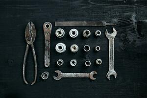 Copy space of working tools on a black wooden surface. Nippers, wrench keys, pliers, screwdriver. Top view. photo