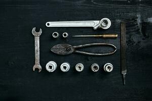 Copy space of working tools on a black wooden surface. Nippers, wrench keys, pliers, screwdriver. Top view. photo