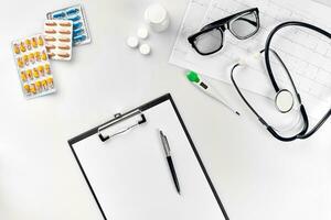 Stethoscope in the office of doctors.Top view of doctor's desk table, blank paper on clipboard with pen. Copy space. Designer's blank photo