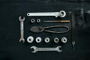 Copy space of working tools on a black wooden surface. Nippers, wrench keys, pliers, screwdriver. Top view. photo