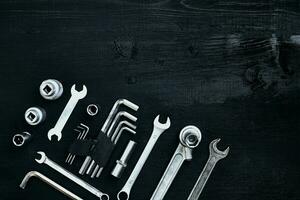 Flat lay of set of tools for car repairing such as wrenches on black wooden background. Top view. photo