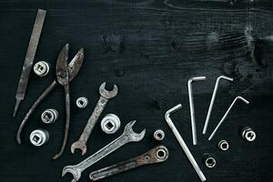 Copy space of working tools on a black wooden surface. Nippers, wrench keys, pliers, screwdriver. Top view. photo